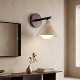 Travertine cone wall sconce with walnut backplate beside a mirror