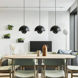 Three bud metal pendant lights hung in a row over a kitchen island
