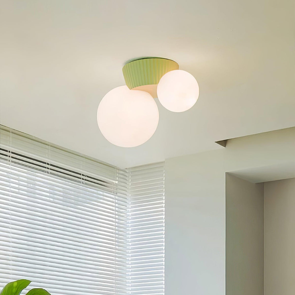 Green canopy globe light lit on a ceiling beside a window with white blinds