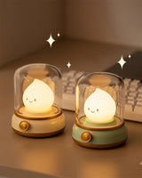Green and beige night lights standing side by side on a desk, both lit