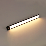 Black light bar glowing warm white against a plain grey wall