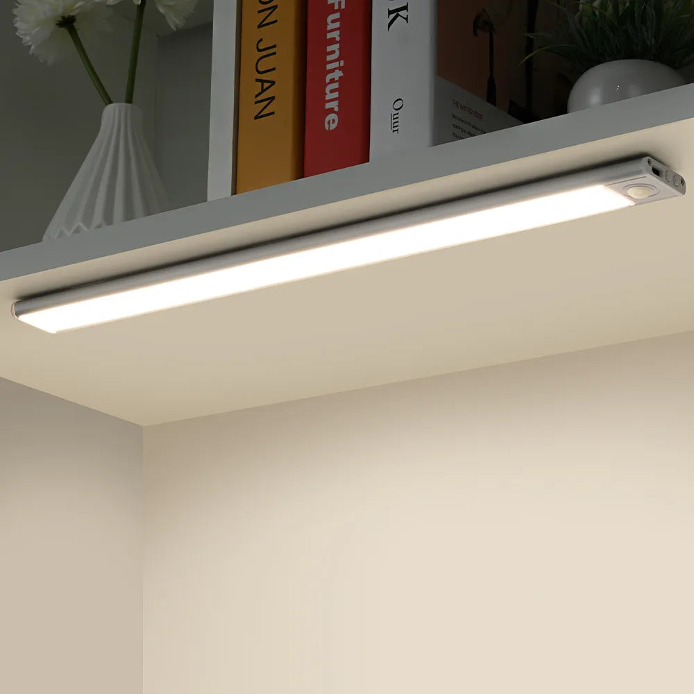 Slim light bar lighting a shelf of books and a small vase