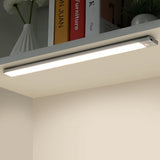 Slim light bar lighting a shelf of books and a small vase