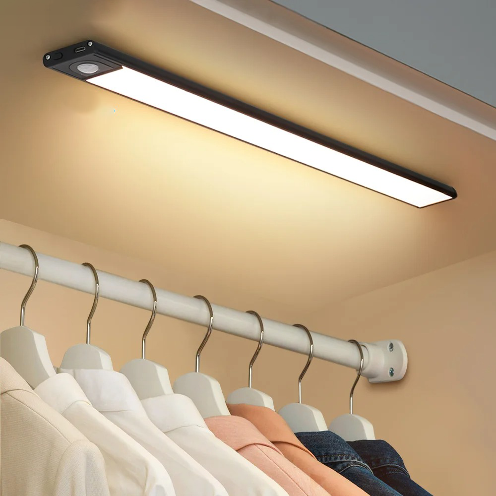 Black sensor bar lighting a rail of coats and hangers below