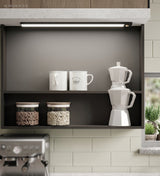 Slim light bar lighting mugs and jars inside a dark open cupboard