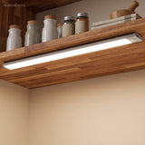 Light bar under a wood shelf lighting spice jars and a worktop