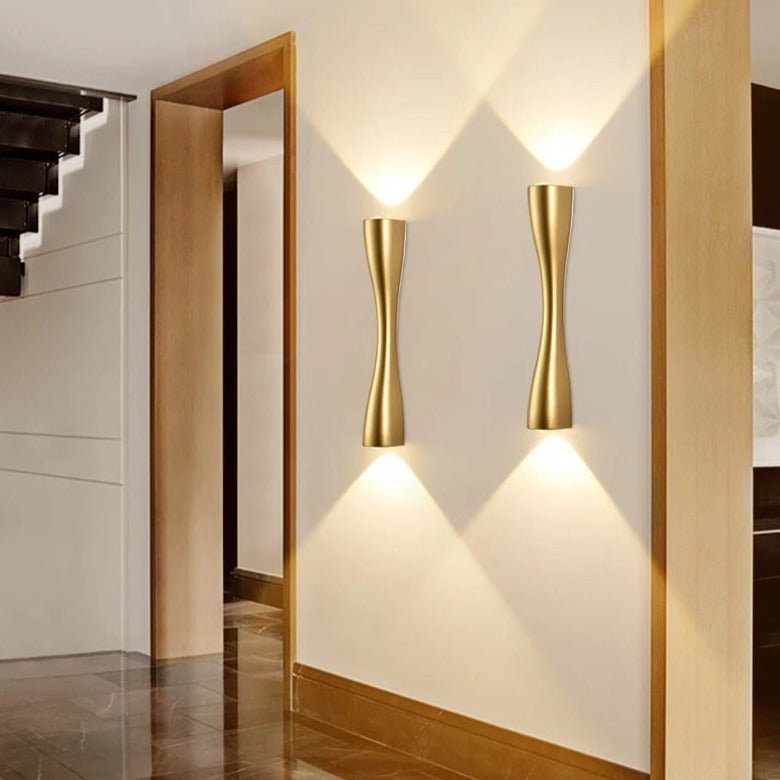 Two gold slim wall lights lit along a hallway with oak door frames
