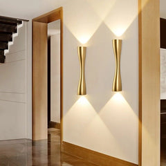 Two gold slim wall lights lit along a hallway with oak door frames