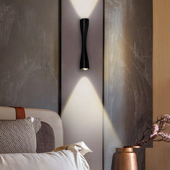 Black slim wall light throwing beams up and down a textured bedroom wall