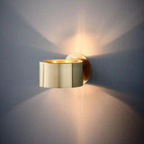 Gold curled sconce with light spreading upward and downward on the wall
