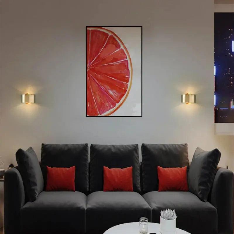 Two sconces lit either side of artwork above a grey sofa