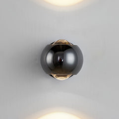 Black orb sconce lit on a plain white wall with beams above and below