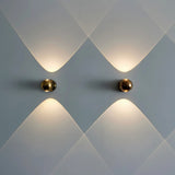 Two gold orb sconces lit side by side on a soft blue wall