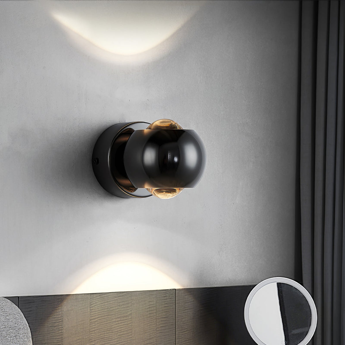 Black orb sconce lit on a grey plaster wall above a wooden console