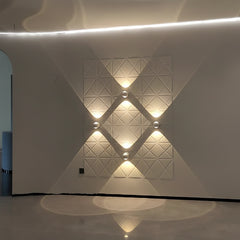 Four white orb sconces lit in a diamond pattern along a corridor wall