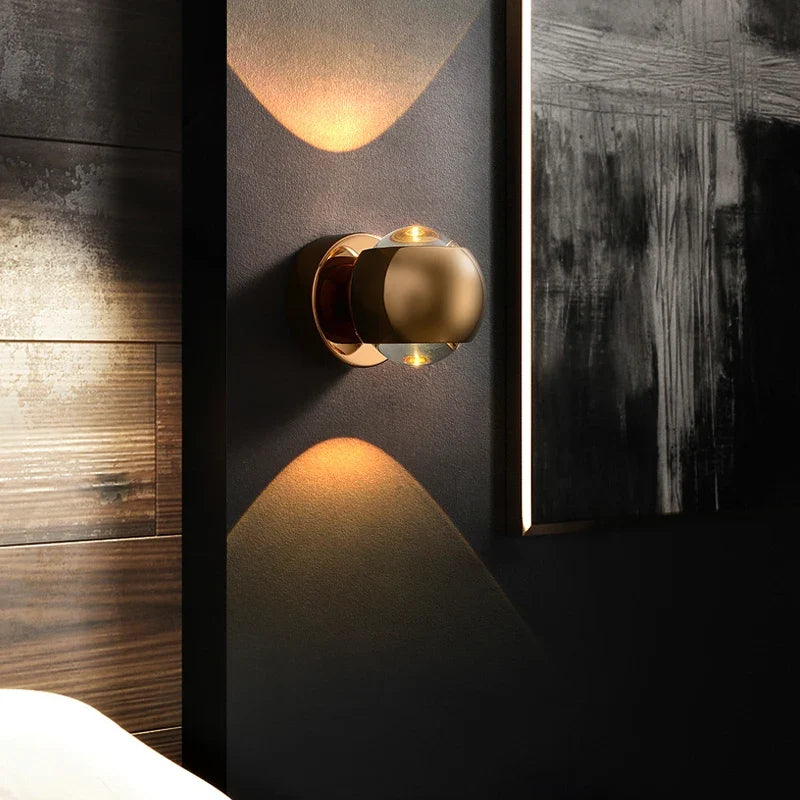 Gold orb sconce lit beside a mirror on a dark wood panelled wall