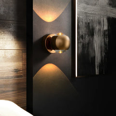 Gold orb sconce lit beside a mirror on a dark wood panelled wall
