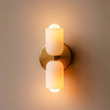 Brass up and down wall light lit, casting warm cones on a pale wall