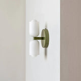 Up and down wall light with an olive green backplate and two white acrylic shades