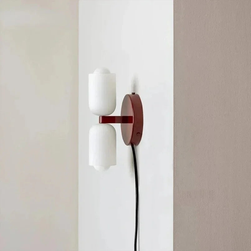 Plug-in up and down wall light with a deep red backplate and trailing cord