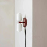 Plug-in up and down wall light with a deep red backplate and trailing cord