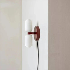 Plug-in up and down wall light with a deep red backplate and trailing cord