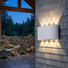Curved white wall light casting fanned beams across timber shingle cladding