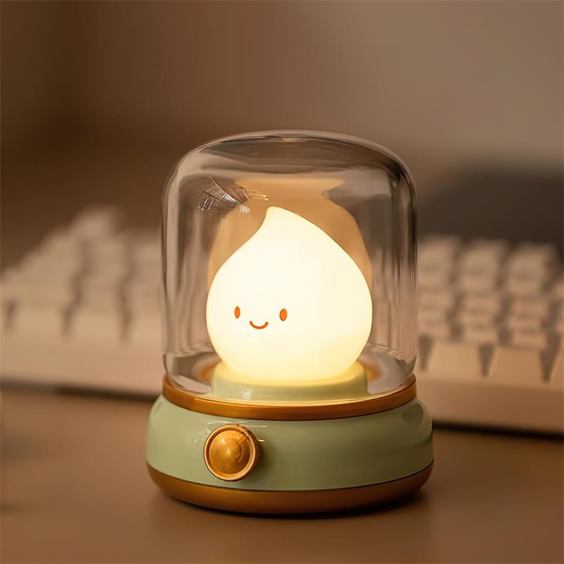 Beige based flame night light glowing on a desk beside a white keyboard