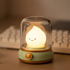 Beige based flame night light glowing on a desk beside a white keyboard