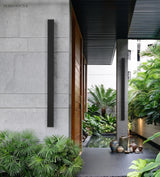 Linear LED wall light on a stone entry wall with tropical planting