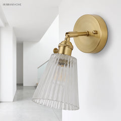 Angled brass wall sconce with ribbed glass shade on a white hallway wall