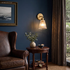 Brass sconce lit on a navy wall above a leather wing chair