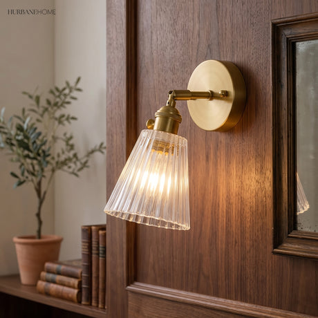 Ribbed glass wall sconce lit on a dark wood panel beside books