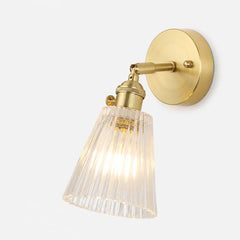 Studio view of the lit brass sconce and clear ribbed glass shade