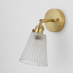 Unlit brass wall sconce seen from the side on a plain background