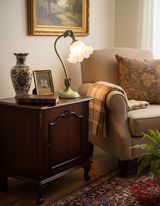 Vintage style flower table lamp on a dark wood cabinet beside a beige armchair