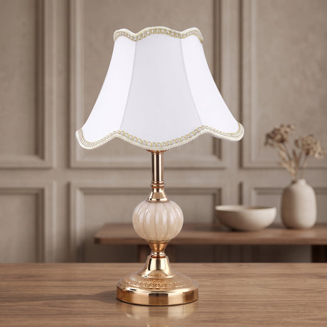 White bell fabric shade on a gold fluted glass base table lamp
