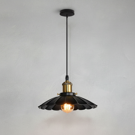 A black pendant light with a scalloped flower-like shade and a brass-colored socket, hanging against a textured white wall.