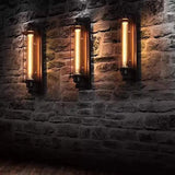 Three cage sconces lit along a dark brick and stone wall