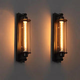 Two black cage sconces lit warm side by side on a grey wall
