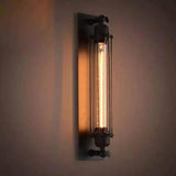 Black cage sconce with an exposed tube bulb glowing warm