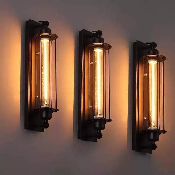 Three black cage wall sconces in a row on a pale grey wall