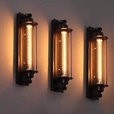 Three black cage wall sconces in a row on a pale grey wall