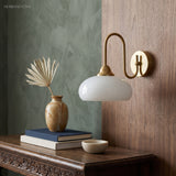 Copper milk glass wall sconce beside a green wall and console table