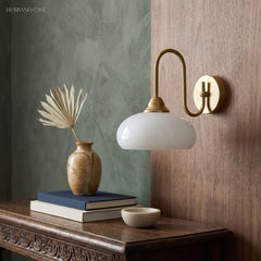 Copper milk glass wall sconce beside a green wall and console table