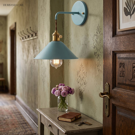 Blue cone shade sconce lit in a hallway above a side table