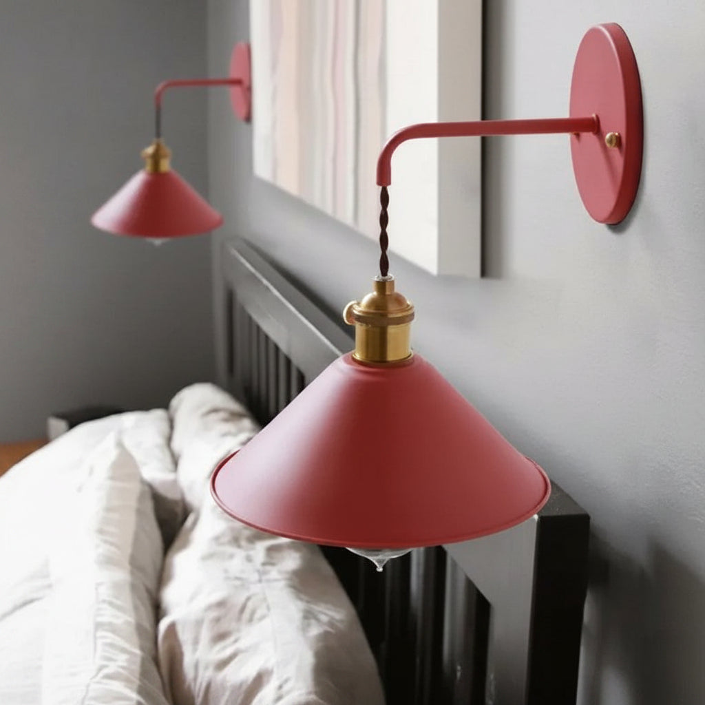 Two coral cone shade sconces lit above a bed with white linen