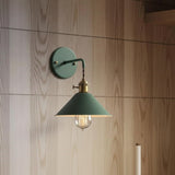 Green cone shade sconce lit against a timber panelled wall