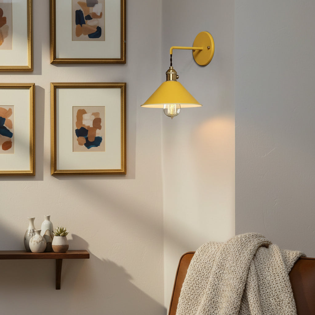 Yellow cone shade sconce lit beside a gold picture frame