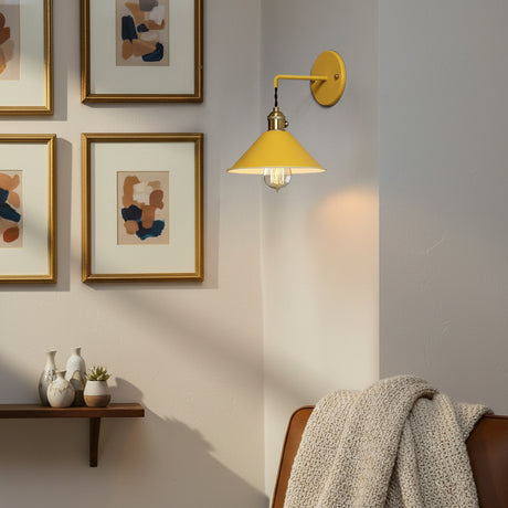 Yellow cone shade sconce lit beside a gold picture frame